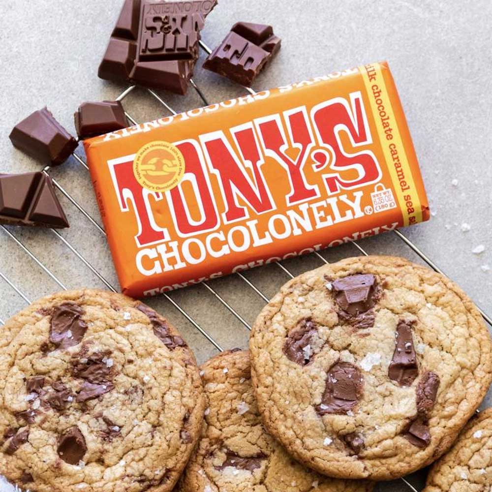 Tony's Chocolonely caramel choclate in orange packet surrounded by chocolate and cookies